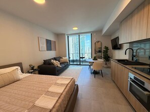 A modern apartment with a large bed, a sofa, a dining area, and a kitchen. - Live the Miami Experience | Prime Location Suite (Miami)