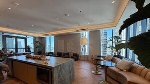 En moderne hotellobby med en marmorø, læderpolstrede møbler og store vinduer med udsigt over byen.