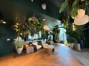 A spacious lounge area with wooden flooring, comfortable seating, and various potted plants. - Live the Miami Experience | Prime Location Suite (Miami)