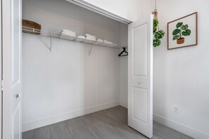 Um closet espaçoso com prateleiras, cabideiro e porta.