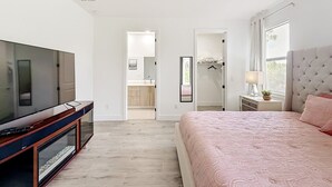 A bedroom with a TV, a bed, a nightstand, and a window. - Cozy Retreat in Port Charlotte (Port Charlotte)