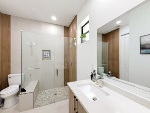 Une salle de bain moderne avec une douche à parois de verre, un lavabo blanc et un grand miroir.