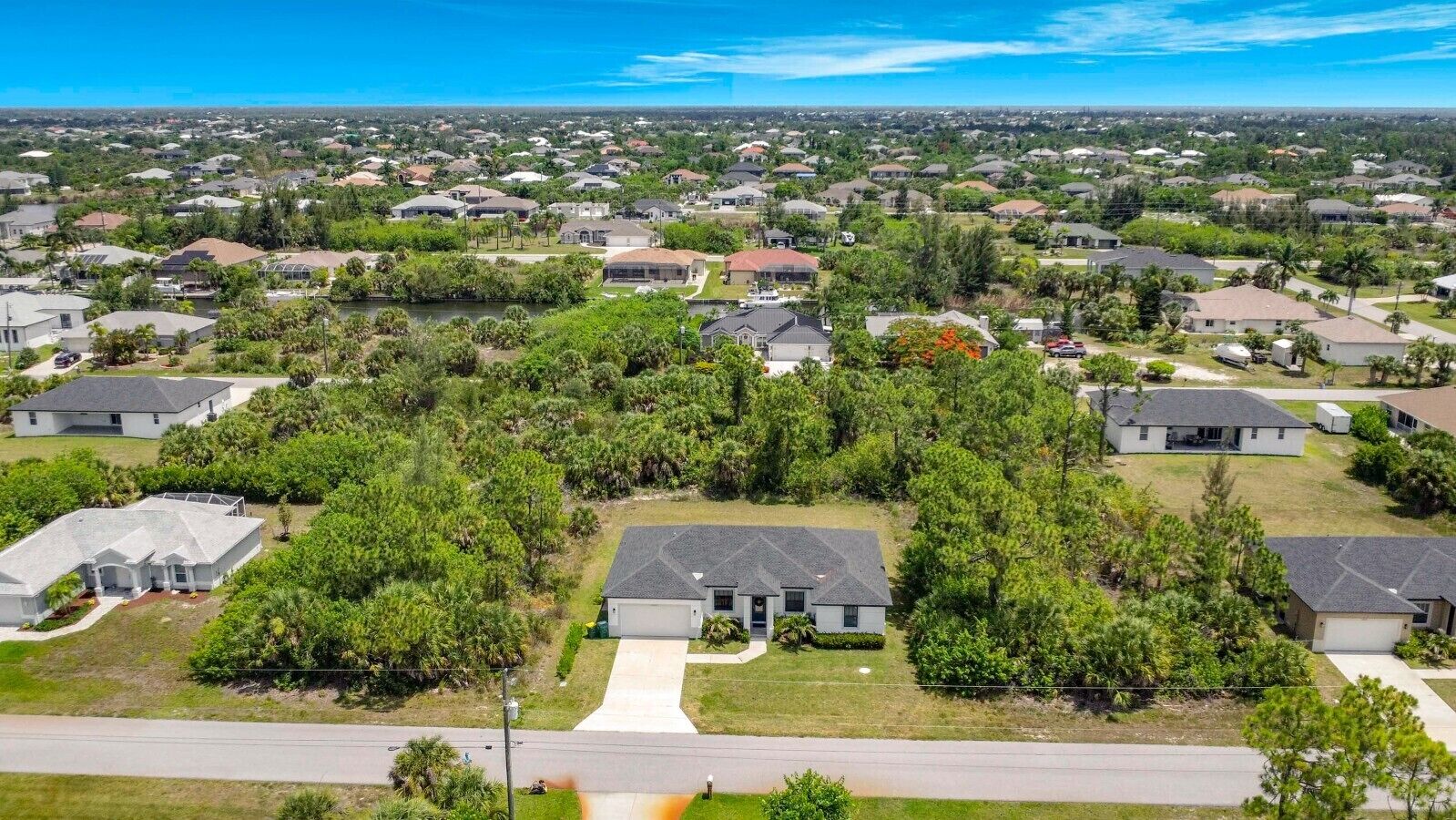 A residential area with houses, green lawns, and a clear sky.