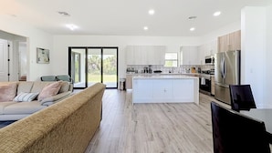 A modern kitchen with a central island, white cabinetry, and stainless steel appliances. - Cozy Retreat in Port Charlotte (Port Charlotte)