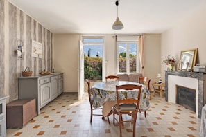 A dining area with a table and chairs, a fireplace, and a view of the outdoors.