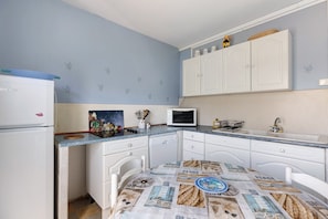 A compact kitchen with a refrigerator, microwave, and white cabinets.