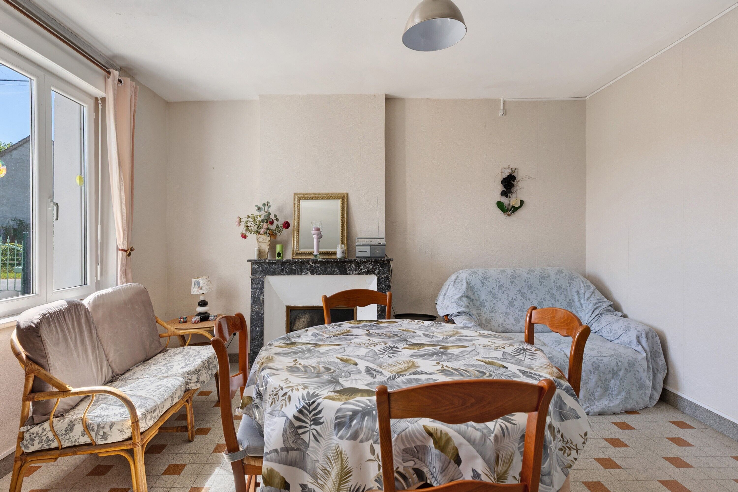 A room with a bed, a sofa, a dining table with chairs, a fireplace, and a window.