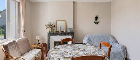 A room with a bed, a sofa, a dining table with chairs, a fireplace, and a window.