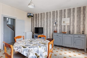 A dining area with a table, chairs, a television, and a cabinet.