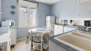 Eine kleine Küche mit Essecke, einem Kühlschrank, einer Mikrowelle und einem Spülbecken.
