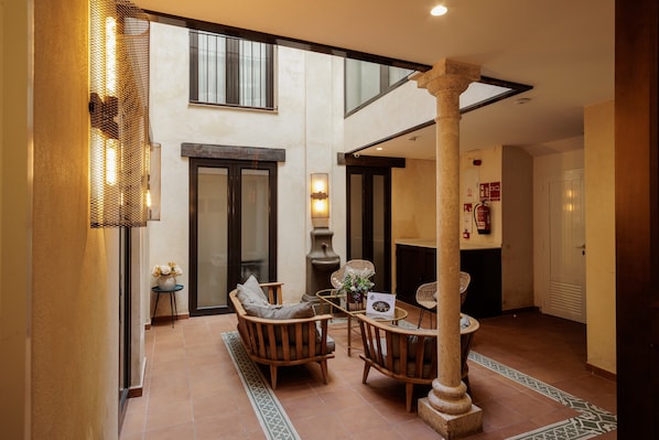 A spacious indoor area with a high ceiling, a fireplace, and a seating arrangement. - Suite Torre del Oro Seville: Pool, Balcony & AC in El Arenal (Sevilla)