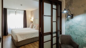 A hotel room with a bed, a chair, a lamp, and a wall with a textured pattern. - Suite Torre del Oro Seville: Pool, Balcony & AC in El Arenal (Sevilla)