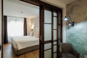 A hotel room with a bed, a chair, a lamp, and a wall with a textured pattern. - Suite Torre del Oro Seville: Pool, Balcony & AC in El Arenal (Sevilla)