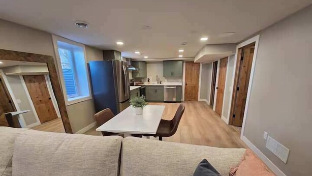 Una sala de estar moderna con un sofá color beige y un comedor con una mesa blanca.