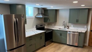 Una cocina moderna con electrodomésticos de acero inoxidable, gabinetes verde claro y piso de madera.