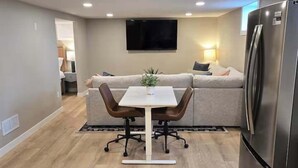Una cocina moderna con una mesa de comedor, sillas, un refrigerador y un televisor de pantalla plana montado en la pared.