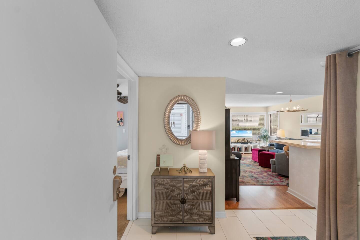 Un pasillo que conduce a una sala de estar con una consola decorativa, un espejo y una lámpara.