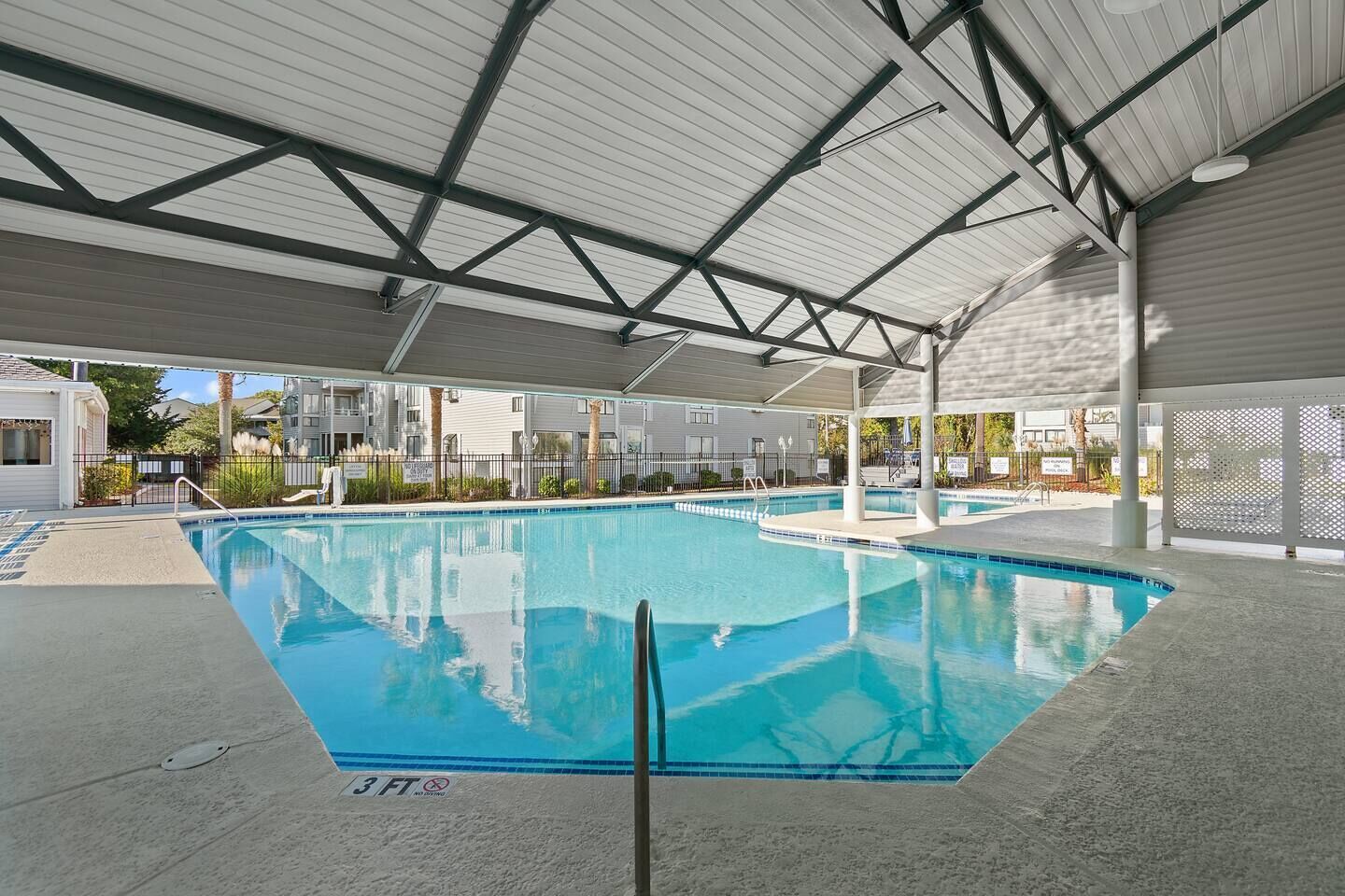 En indendørs swimmingpool med et tag og tydelige kantlinjer, samt en dybdemarkering på 90 centimeter.
