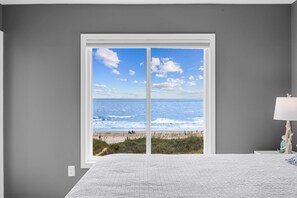 A bedroom with a large window overlooking a beach. - Totally Beachin' - Oceanfront, King Bed, Pool (North Myrtle Beach)