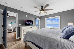 A bedroom with a bed, a ceiling fan, a TV, and a view of the ocean. - Totally Beachin' - Oceanfront, King bed, Pool (North Myrtle Beach)