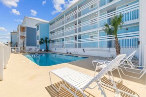 A hotel pool area with a clear blue pool, white lounge chairs, and a multi-story building with balconies. - Totally Beachin' - Oceanfront, King bed, Pool (North Myrtle Beach)