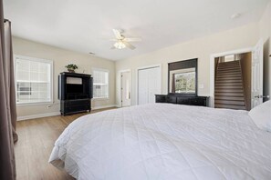 Ein Schlafzimmer mit einem großen Bett, einem Deckenventilator, einem Schminktisch und einem Fenster.