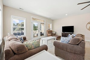 A living room with a sofa set, a coffee table, and a television. - 5 Bdrm Home w/ Epic gameroom, pool, put put, 7 bds (North Myrtle Beach)