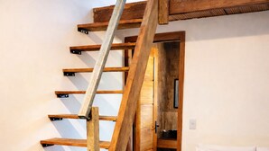 A bedroom with a wooden staircase, a bed with a patterned pillow, and a wooden wardrobe. - Cozy and stylish house in Alter do Chão. (Alter do Chão)