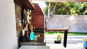 A patio area with a white refrigerator, a brick oven, and a wooden table. - Cozy and stylish house in Alter do Chão. (Alter do Chão)