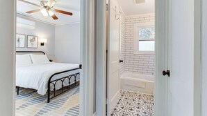 A bedroom with a bed, a ceiling fan, and a bathroom with a bathtub and a window. - Updated, Wi-Fi, Coffee, Kitchen, Comfortable Bed (Athens)
