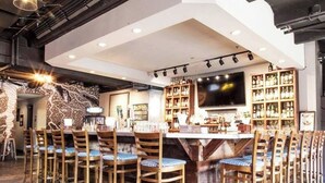 A bar area with wooden chairs and a bar counter, surrounded by shelves of bottles. - Updated, Wi-Fi, Coffee, Kitchen, Comfortable Bed (Athens)