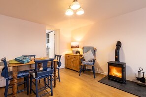 Una habitación acogedora con una mesa de madera, sillas, chimenea y una lámpara.