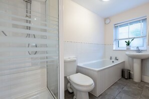 A modern bathroom with a glass shower enclosure, a white toilet, a bathtub, and a sink.