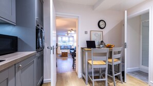 Une cuisine moderne avec des meubles gris, un four à micro-ondes et un coin repas comprenant une table et des chaises.