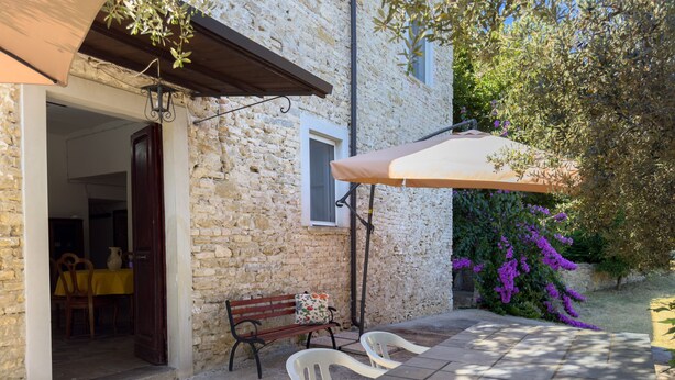 Un edificio de piedra con un patio, una banca y una mesa con sillas.