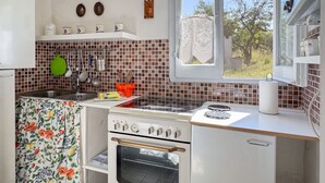 Una cocina con estufa, horno, lavaplatos y ventana.
