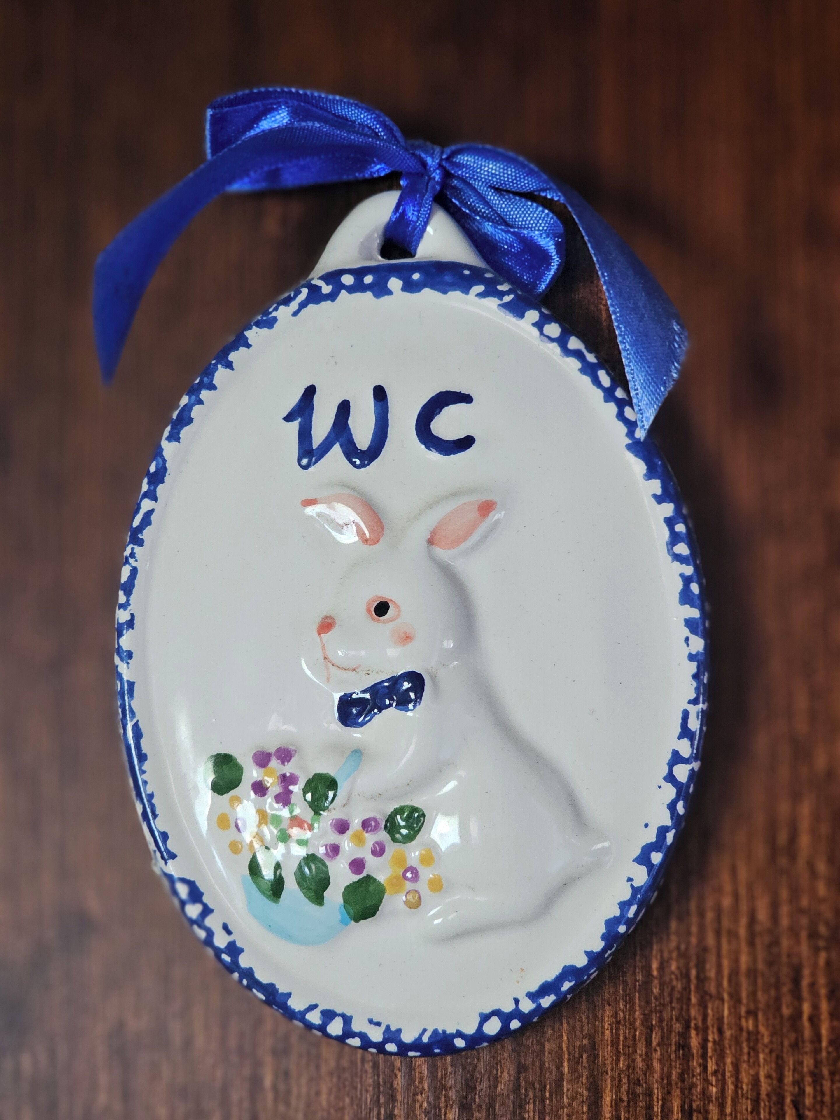 Uma ornamentação de coelho de cerâmica com uma fita azul.