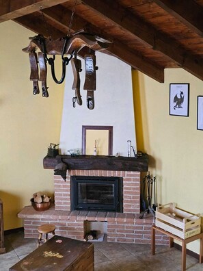 A rustic interior with a brick fireplace, wooden beams, and a hanging light fixture. - The Dragon of the Lake - a vacation home on Lake Orta (Boleto)