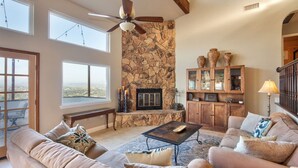 A spacious living room with a stone fireplace, large windows, and a ceiling fan. - Exceptional city light views- 5 min to Old Town (Temecula)