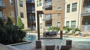 Uma área de piscina no terraço com espreguiçadeiras, uma cadeira suspensa e um deck de madeira.