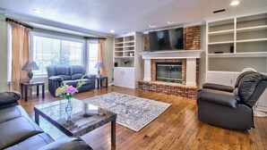 A living room with a fireplace, leather sofas, a coffee table, and a TV. - Rancho Vista Estate on 3 acre, Private grapevines (Temecula)