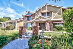 A two-story house with a brick facade, a front porch, and a small garden with a pathway leading to the entrance. - Rancho Vista Estate on 3 acre, Private grapevines (Temecula)