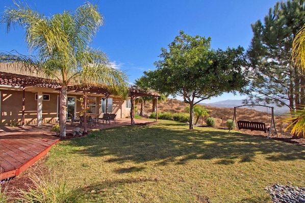 Uma casa com alpendre, área de estar externa e vista para as colinas.