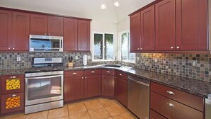 Una cocina moderna con armarios de madera oscura, electrodomésticos de acero inoxidable y salpicadero de azulejos.