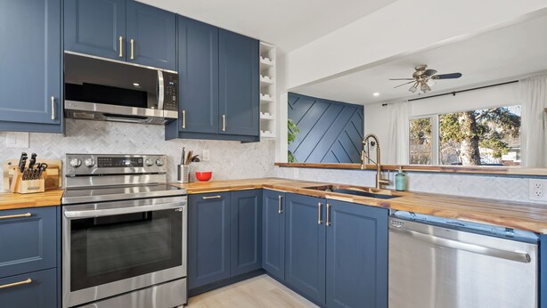 Eine moderne Küche mit blauen Schränken, Edelstahlgeräten und einer Holz Arbeitsplatte.