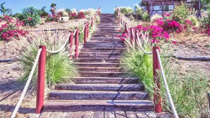 Un escalier en bois, avec des rampes rouges, mène à un bâtiment doté d’un toit en bois.