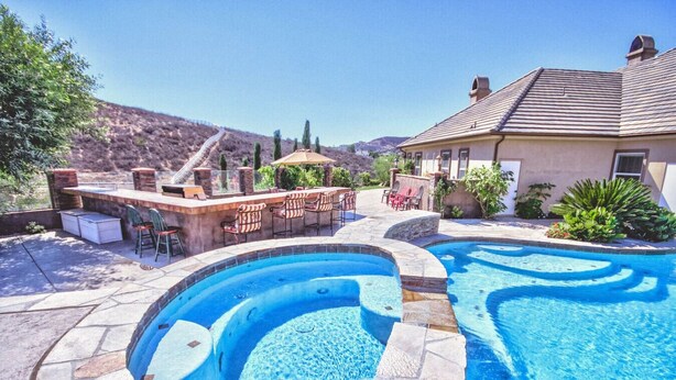 Un jardin avec une piscine, un jacuzzi et un espace barbecue.