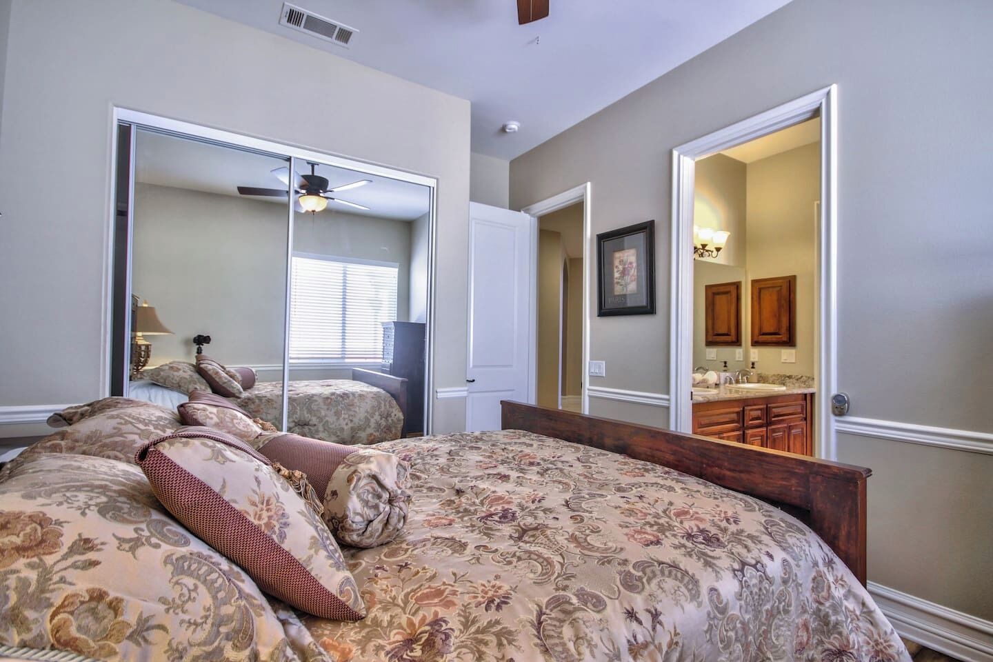 Une chambre avec un grand lit, un ventilateur de plafond et une vue sur la salle de bain.