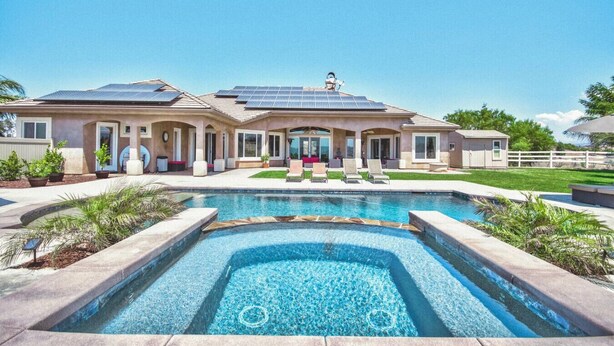 Ein zweistöckiges Haus mit Schwimmbad, Solaranlage und einem eingezäunten Garten.