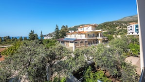 Un edifici d'àmbitió amb balcons, envoltat d'oliveres i un cel blau i clar.